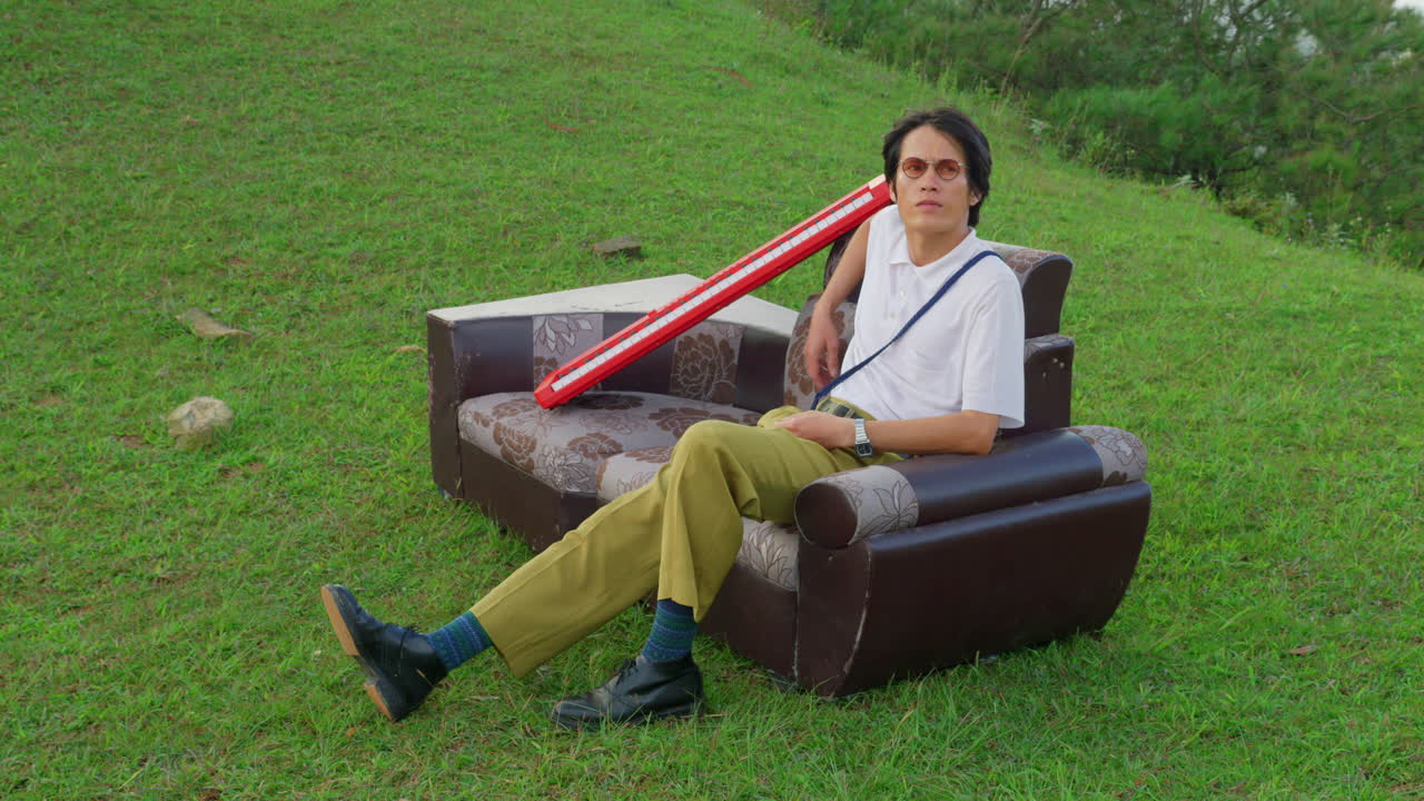 Man Relaxing on a Sofa in a Grassy Field