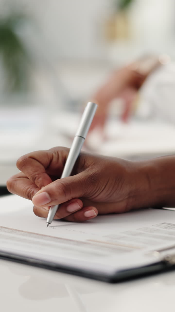 Close-up of a Hand Writing on a Document with a Pen