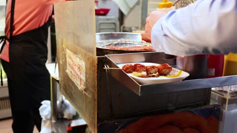 vendor prepares skewers with sauces at food stall