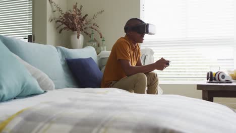 video de un niño afroamericano feliz usando auriculares vr y jugando videojuegos en casa