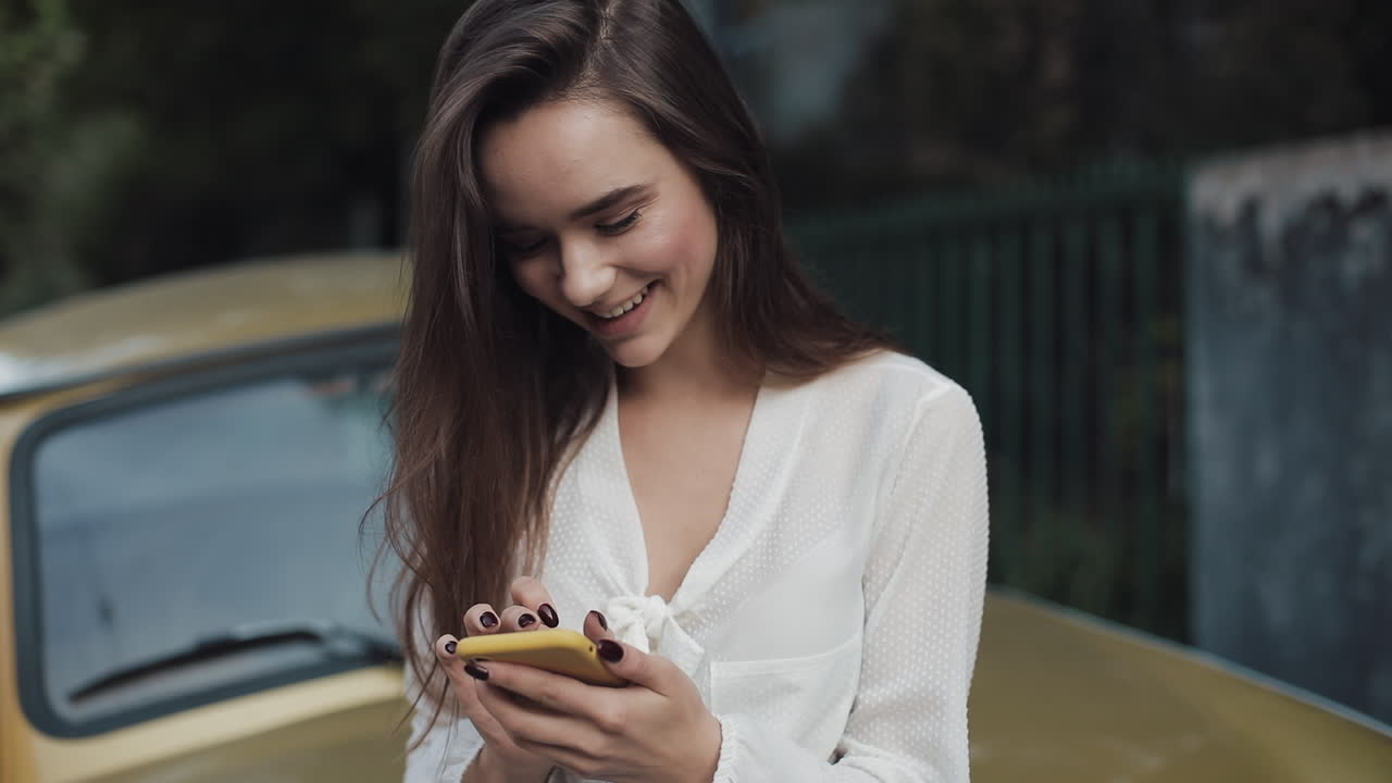 Woman using her mobile phone next to a car