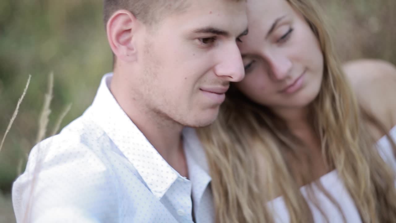 Happy Young Couple Drinking Wine Outside. Romantic evening. Charming couple near a fire while camping drinking wine