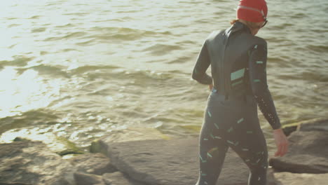 female triathlete in swimsuit walking to lake