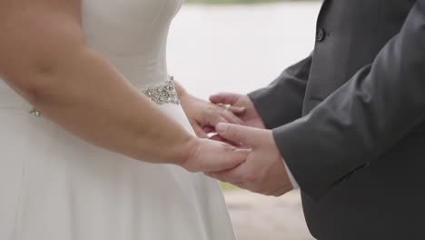 primer plano, pareja heterosexual anónima de talla grande tomándose de la mano el día de la boda, cámara lenta