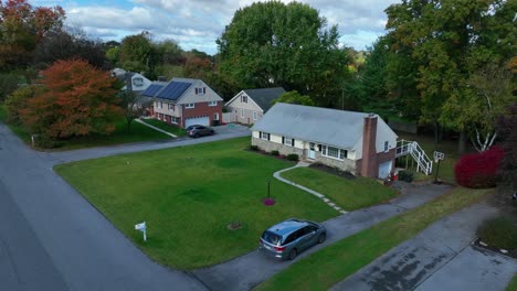 minivan entering driveway of american home during autumn day