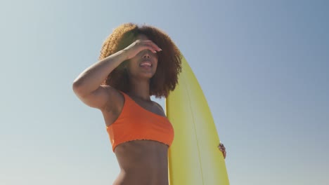 african american woman looking at the sea view with surfboard