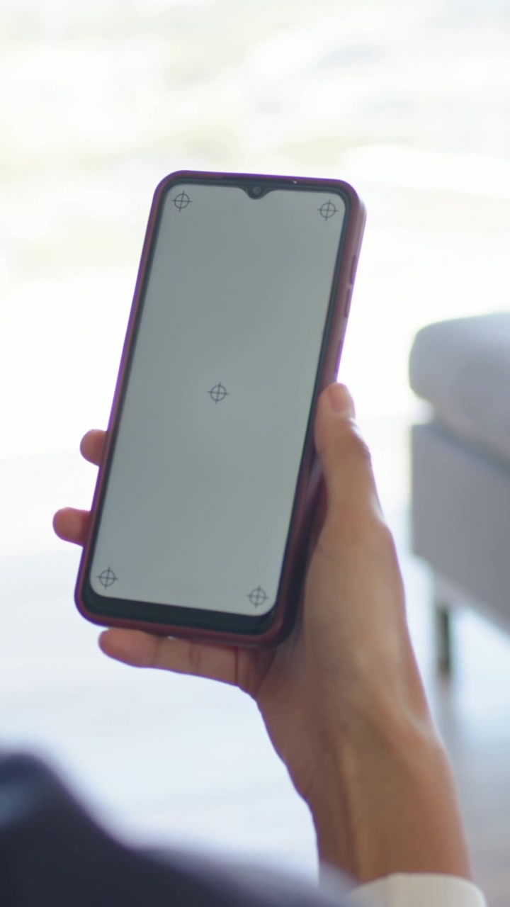 Video verticale: Persona che si sistema, tiene il telefono con custodia viola sul divano, reagendo a un mirino.