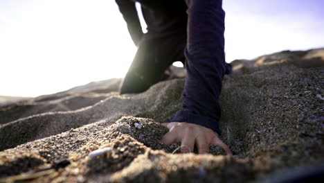 Nahaufnahme-Erschöpfter-Mann,-Der-Mit-Seiner-Hand-Auf-Strandsand-Fällt