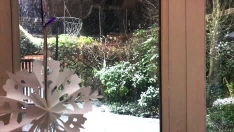 snow falling past christmas snowflake decoration into backgarden with netball hoop