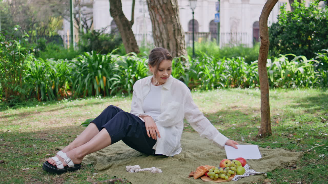 Reading woman caressing dog on picnic blanket sunny summer day. Happy lady