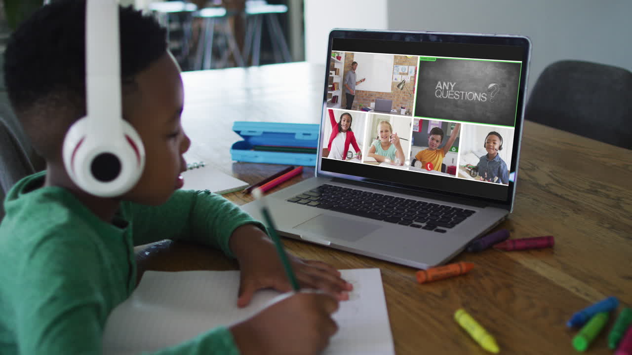 Schoolboy using laptop for online lesson at home, with diverse teacher and class on screen