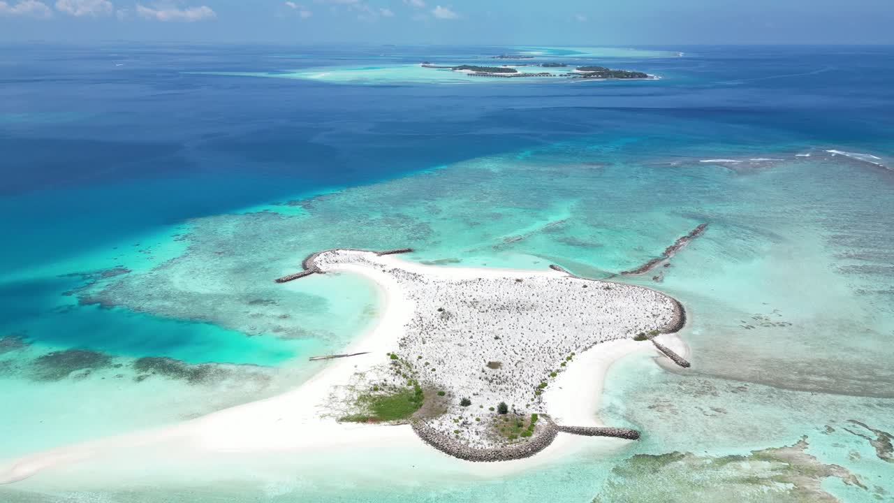 A remote tropical island with white sandy beaches surrounded by clear turquoise water.