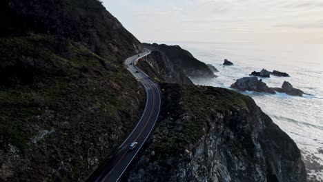 epic drone view of california’s pacific coast highway winding along steep cliffs and ocean