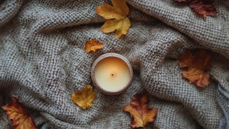 una acogedora vela de otoño con hojas de otoño