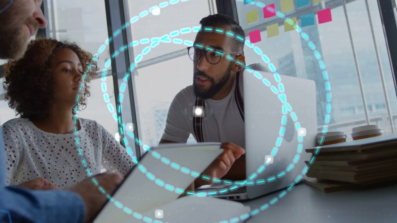Center man leaning, tapping laptop, starting turquoise rings overlay covering business meeting