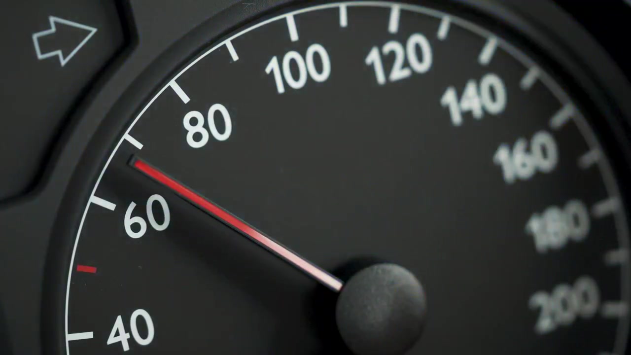 Close-up of a car speedometer showing approximately 60 kmh with a red needle and blurred blue police lights in the background. Concept image for speed control, traffic enforcement, road safety, polic