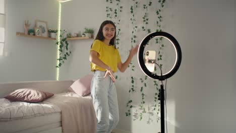 teenage caucasian girl dancing and recording video for social media using ring light