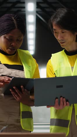 vertical video team of diverse workers handling tracking software for parcel status on tablet
