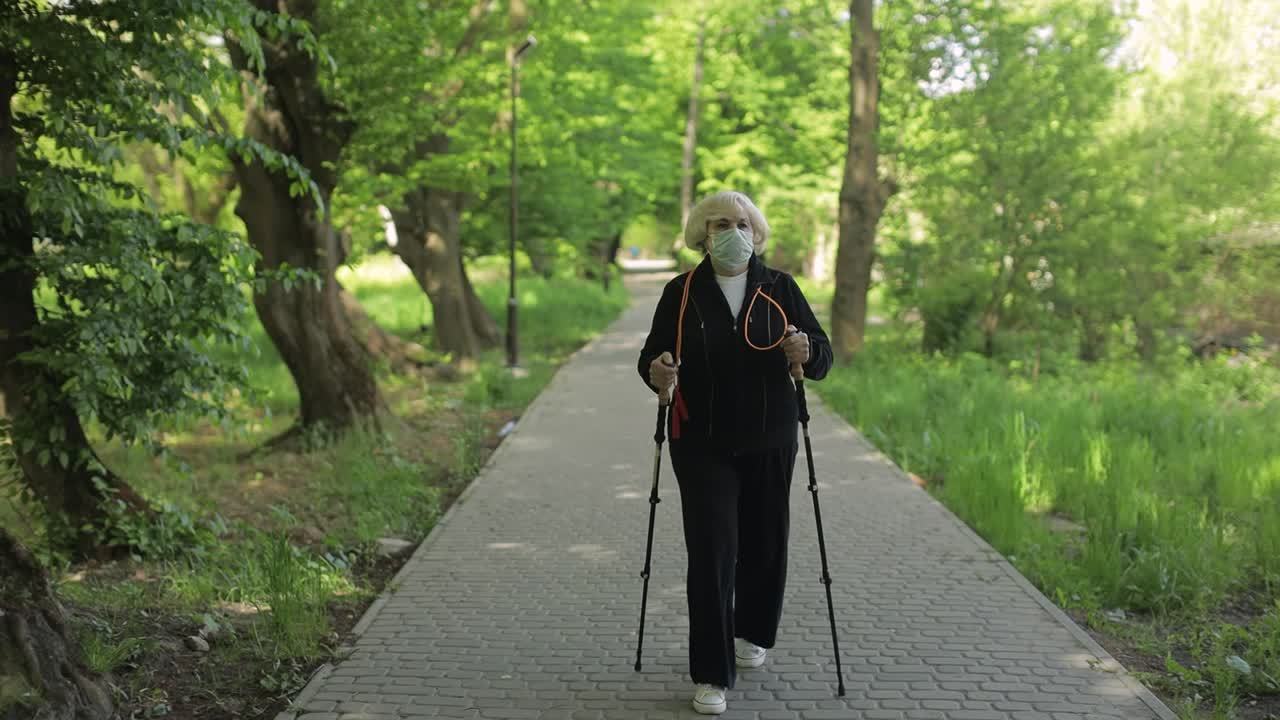 Donna anziana che cammina nel parco indossando una mascherina