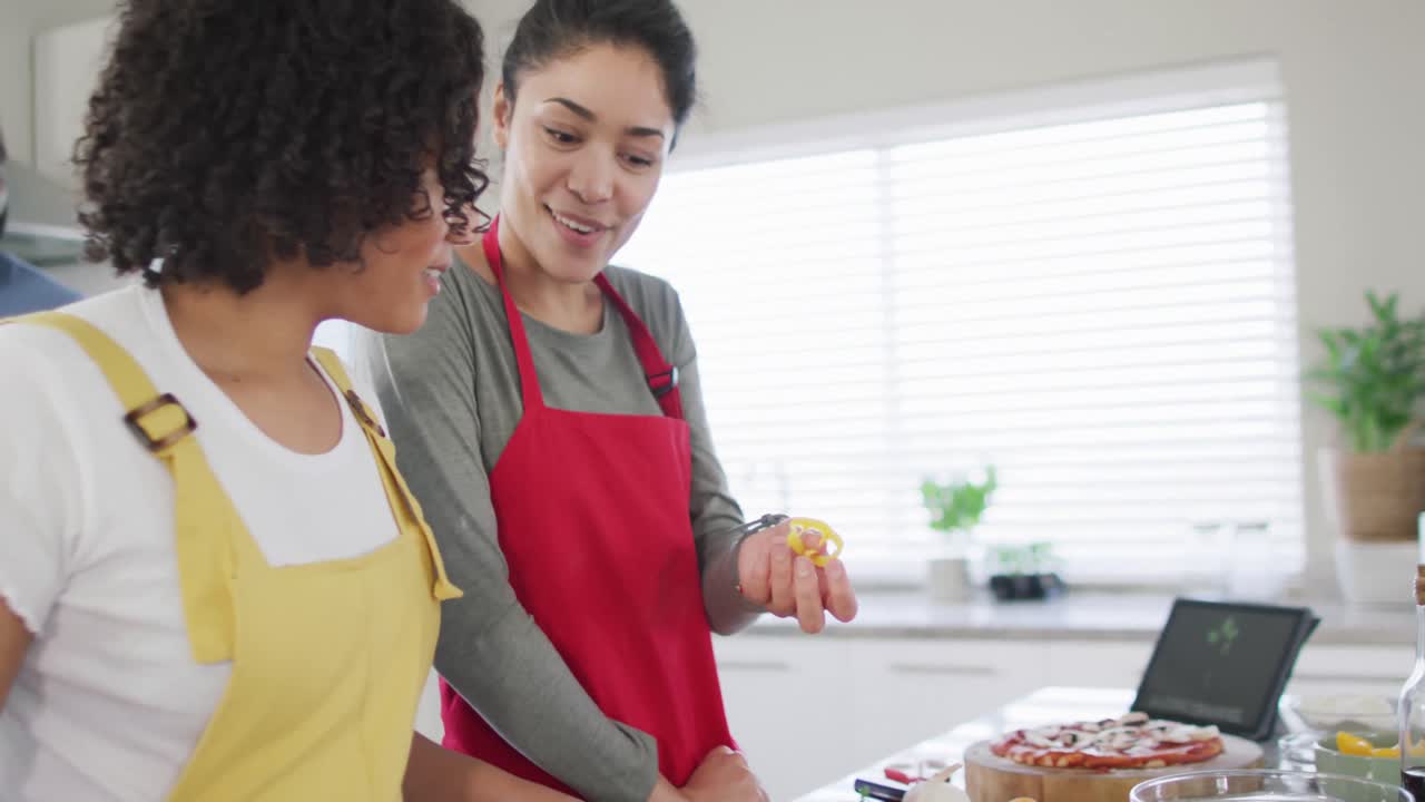 sonriendo diversas amigas y amigos con computadora portátil haciendo pizza en la cocina, en cámara lenta