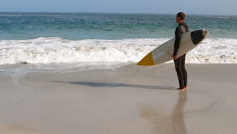 Man-in-wet-suit-holding-surfboard