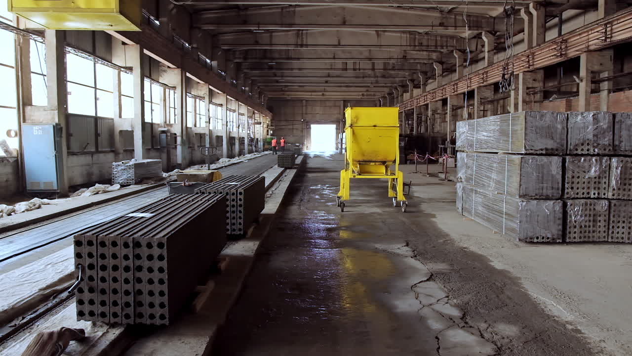 Plant for production of concrete slabs indoors. Reinforced concrete blocks folded in the large hangar. Building materials on the factory.