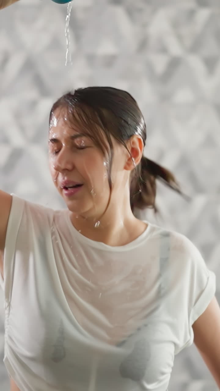 여성은 머리에 물을 부어 냉각 의식을 포함합니다. 스포츠 여성은 피곤함을 느니다. 피트니스 구역에서 운동 중에 과열을 능숙하게 해결합니다.