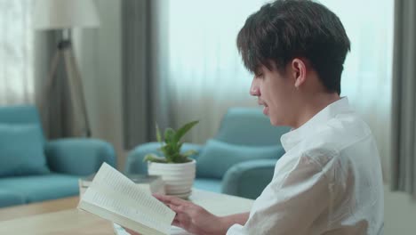 close up of asian man student reading a book while studying at home