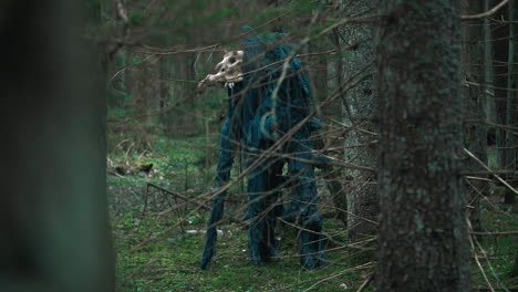 Mystical-monster-with-skull-of-animal-standing-in-dense-forest