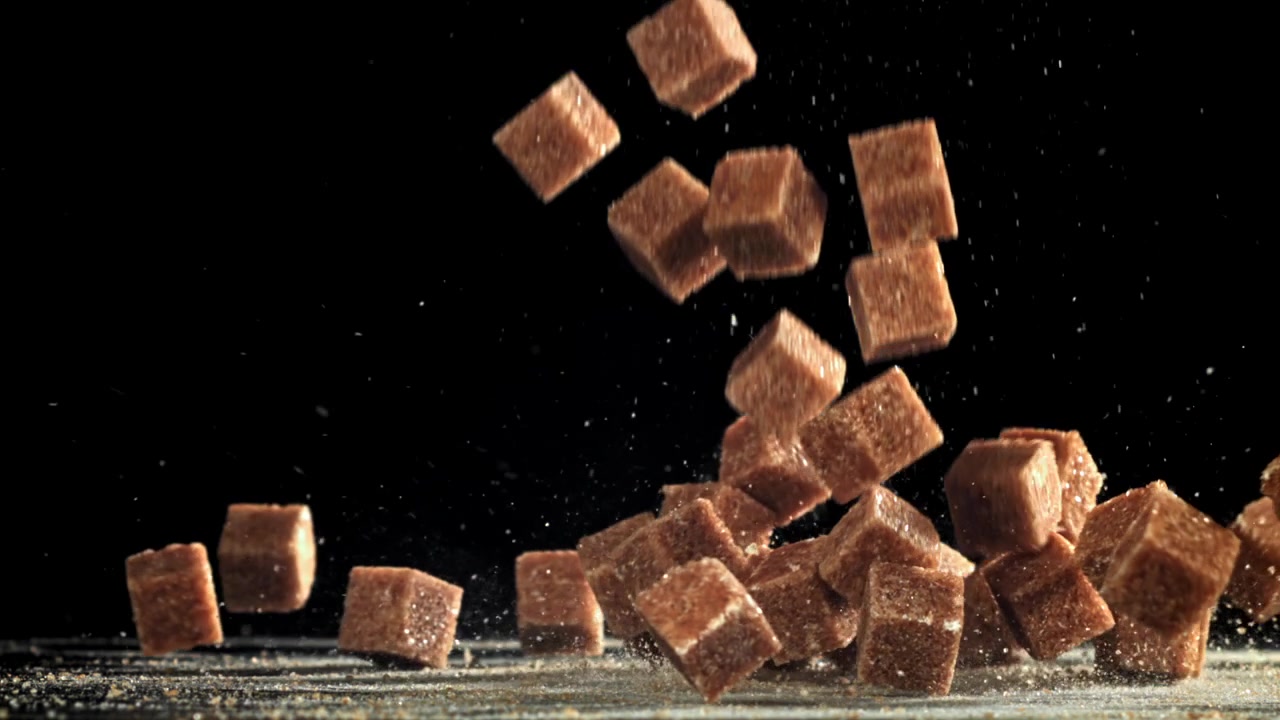 Brown Sugar Cubes Falling in Slow Motion on Black Background