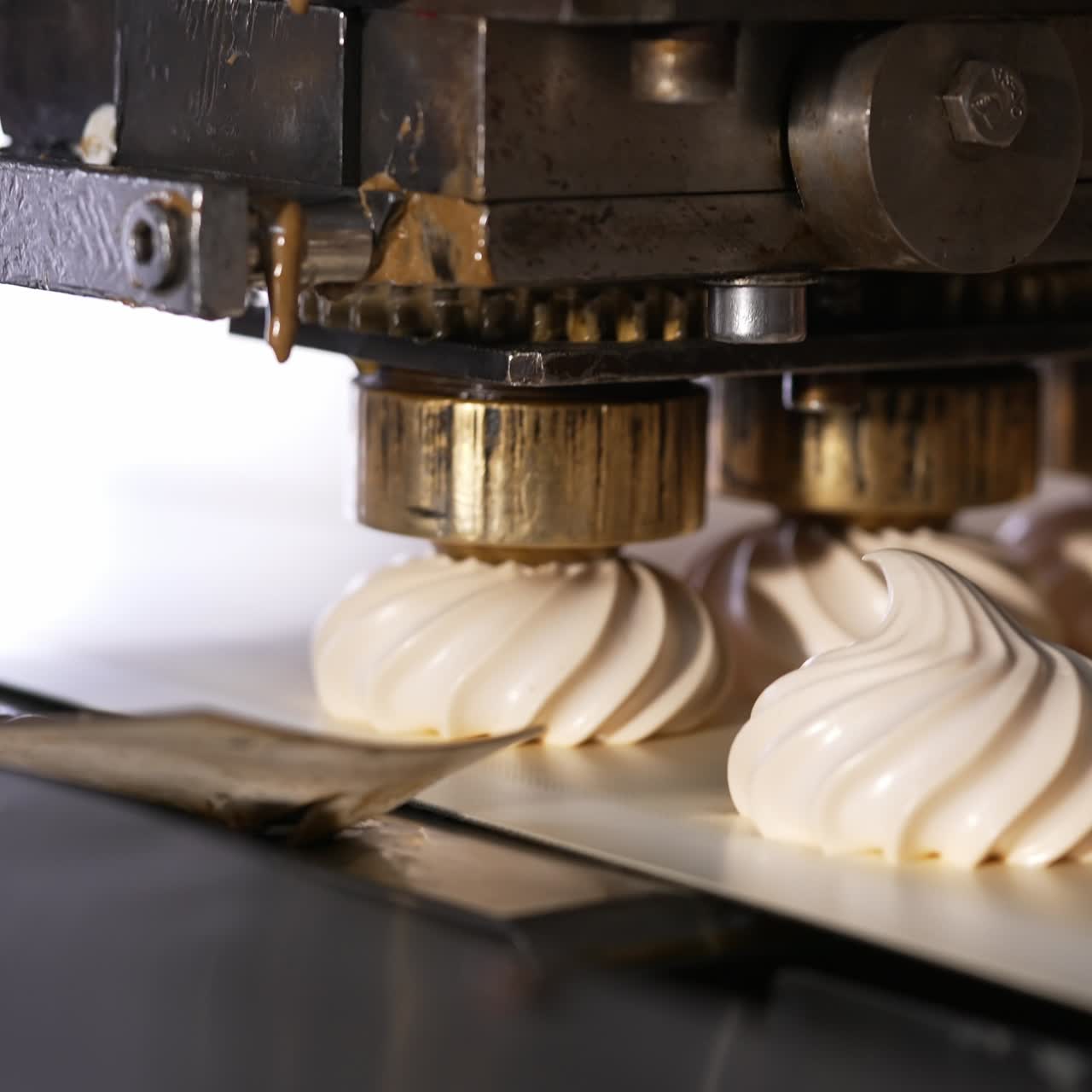 Vanilla marshmallows are squeezed on the conveyor belt. Automated line for zephyr manufacturing at food factory. Close up