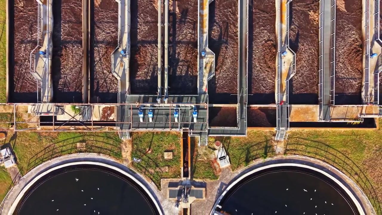 Water treatment facility processes wastewater with multiple tanks and pipes in a modern setting