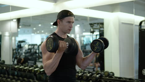 Athlete-exercising-with-dumbbells-in-indoor-gym