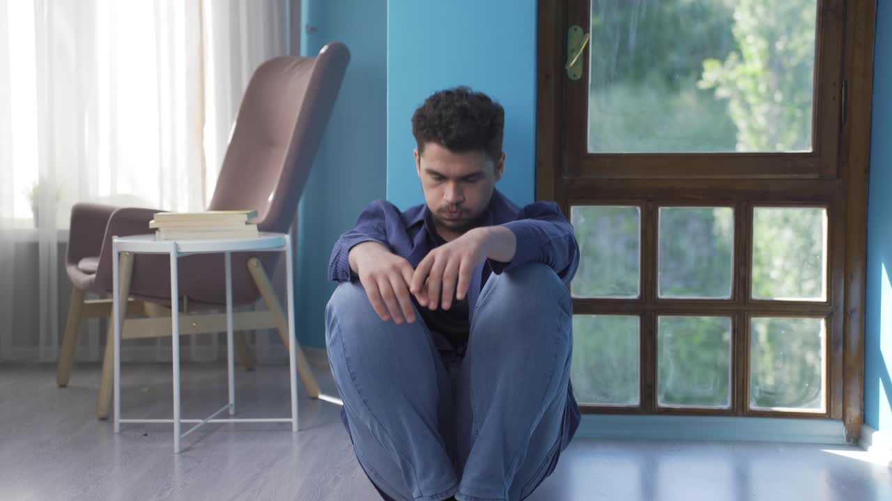 hombre deprimido. se sienta junto a la pared.