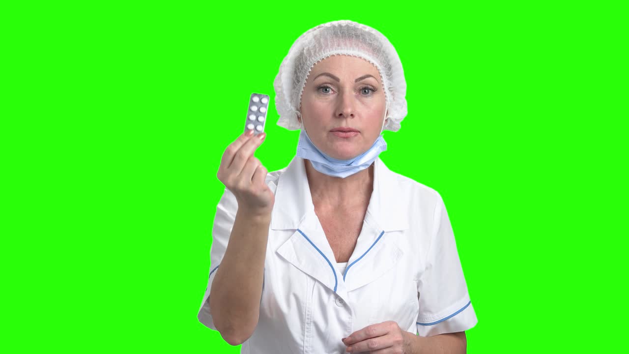 Lady doctor with pills on green screen.