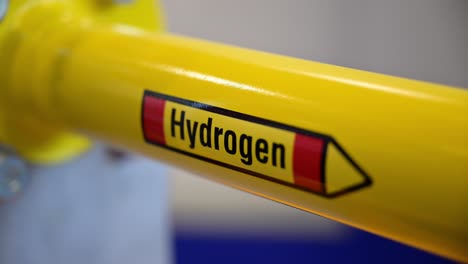 the word hydrogen on a yellow pipe which is part of a demonstrator of special shut-off valves on a trade fair, focus pull