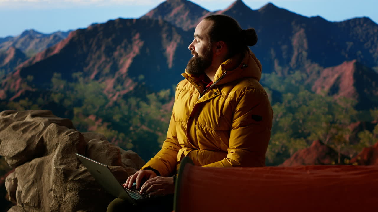 el joven explorador sigue trabajando en la cima de la montaña con internet en todas partes.