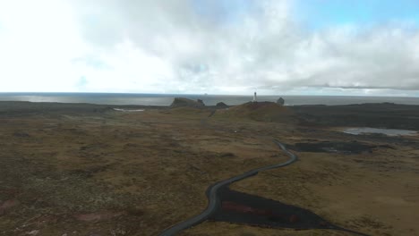 wide aerial shot of a lighthouse with bleak surrounding coastline