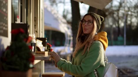 woman choosing goods in street kiosk on winter walk. smiling to the camera