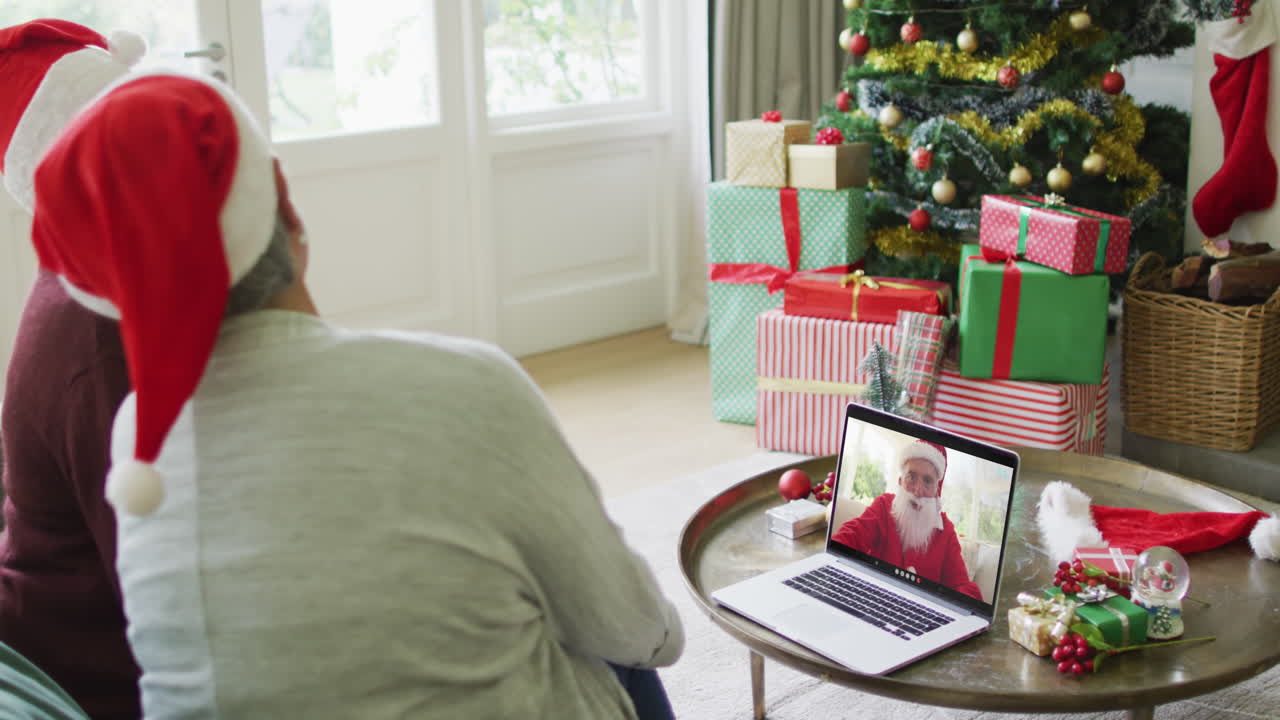 diversas amigas mayores usando una computadora portátil para una videollamada de navidad con happy santa en la pantalla