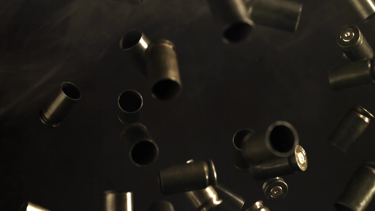 Slow Motion Bullet Casings Falling with Smoke on Dark Background