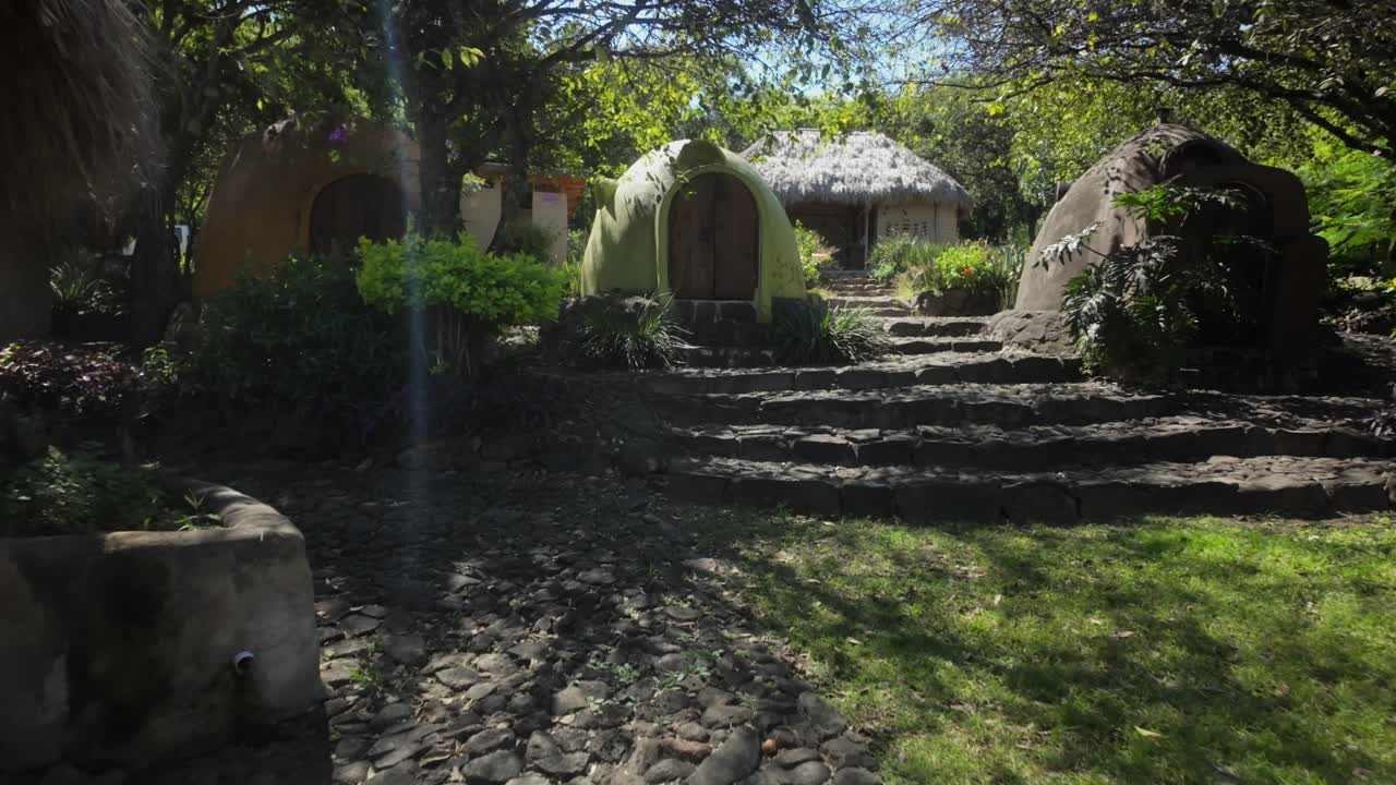 Sustainable dome-shaped SuperAdobe structures with stone steps and greenery