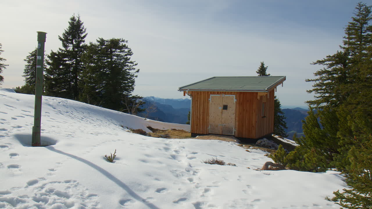 Wooden Hut Surrounded By Pine Trees On Snowy Ridge In The Bavarian Alps, Germany. wide shot
