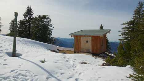 wooden hut surrounded by pine trees on snowy ridge in the bavarian alps, germany. wide shot