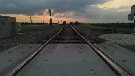 drone shot tracking low just above railroad tracks after sunset in texas, u