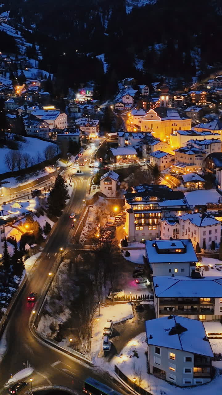 Aerial drone view of the Ortisei town covered in snow at night, within the Dolomites, in northern Italy. Vertical