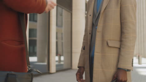 two multiethnic businessmen shaking hands outdoors in city