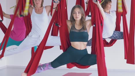 mujeres serias y fuertes de pie en la asana de guerrero de yoga de mosca