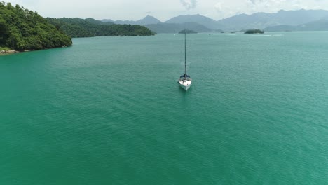 Toma-Aérea-De-Un-Dron-De-Un-Velero-Que-Llega-A-Una-Hermosa-Isla-Tropical-Con-Vegetación-Nativa-Brasileña-Y-Playa-Desierta