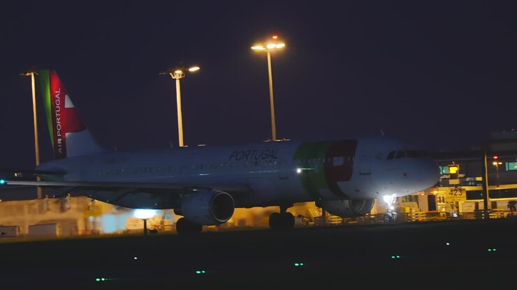 Aeromobile wide-body TAP Air Portugal parcheggiato di notte al terminal di Lisbona.